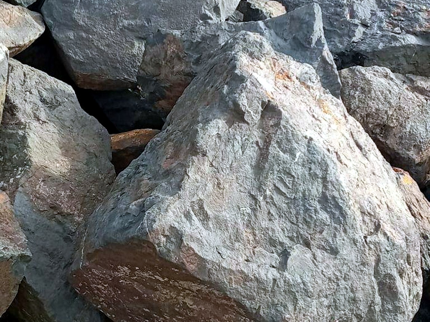 Close-up of large grey run-of-mine rock boulders stacked on a crusher feed pad