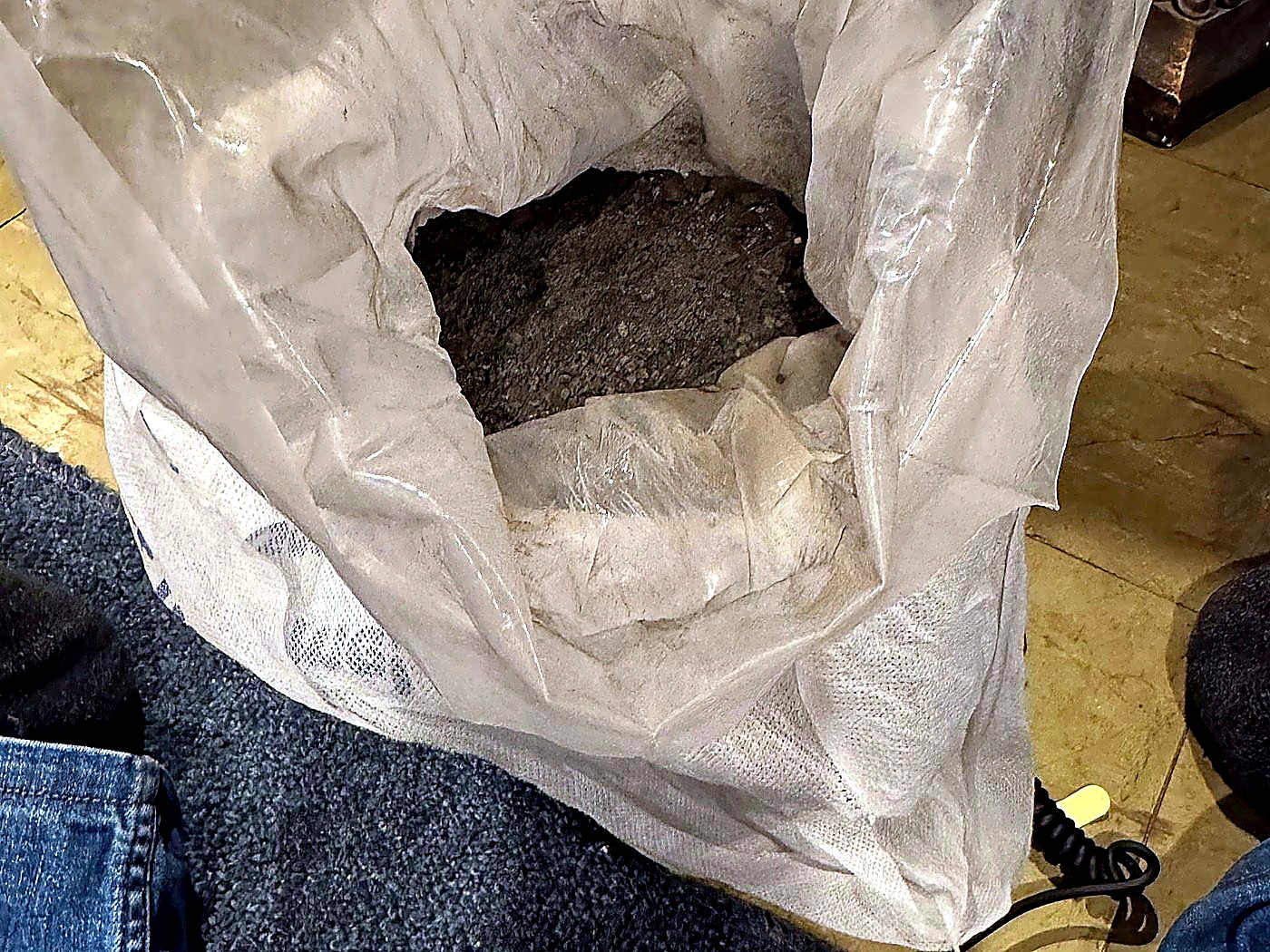 An open sack of grey mineral concentrate photographed during a second verification weighing