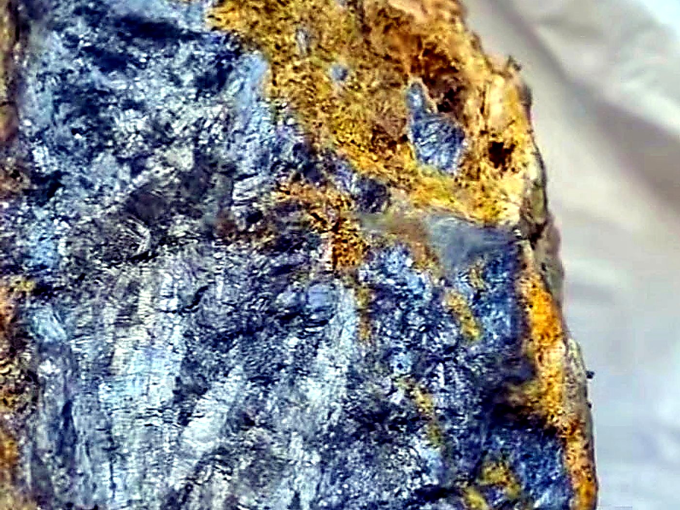 Rough grey and gold-flecked polymetallic sulphide ore specimen photographed close up in a sample bag