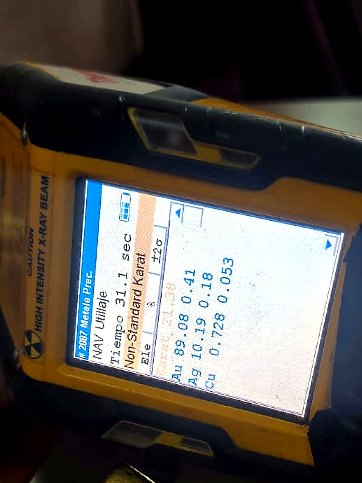 Small rectangular refined gold bar photographed beneath a handheld XRF analyser reporting 89 percent gold