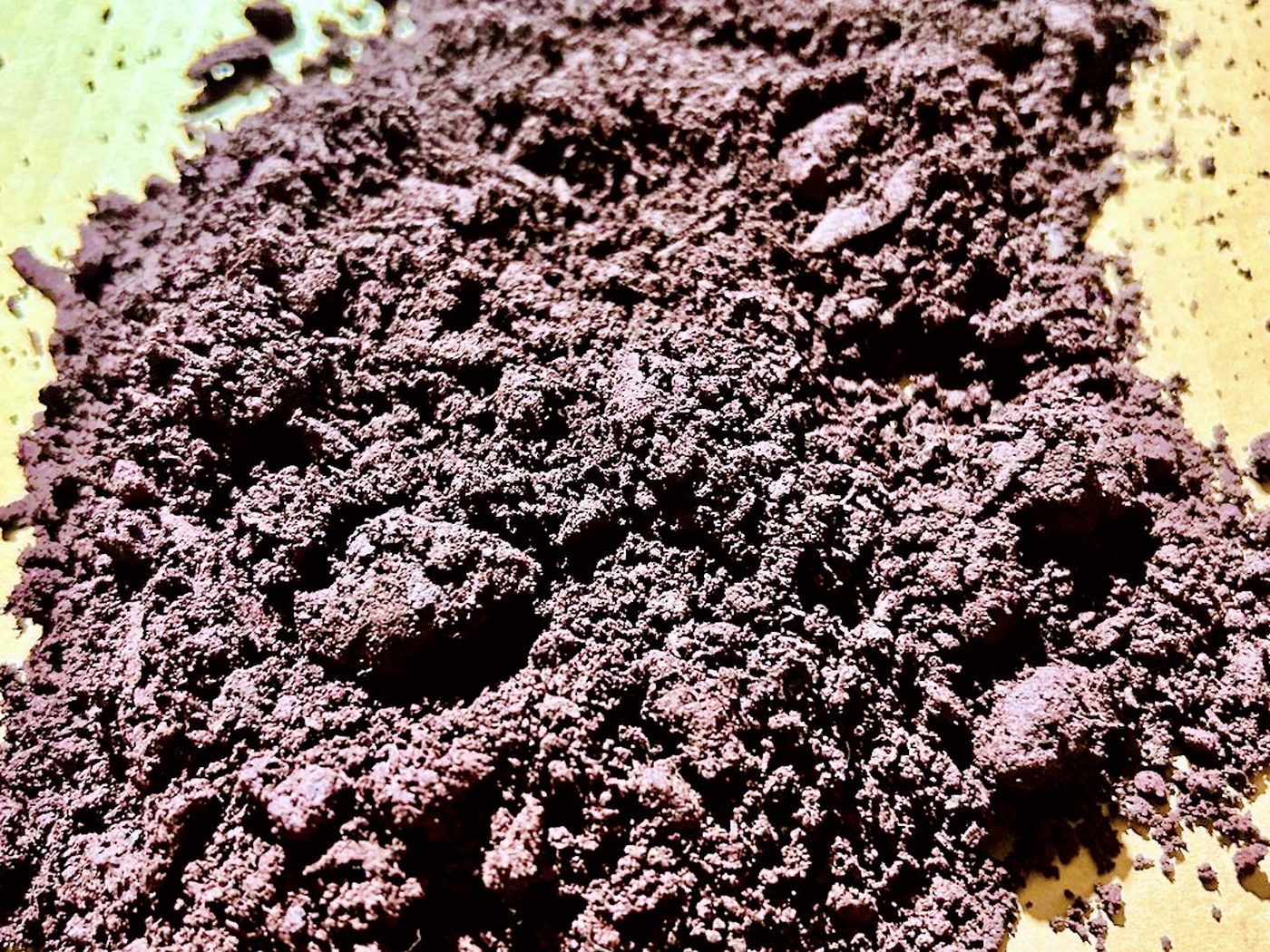 A spread of fine dark reddish-brown ground mineral concentrate powder ready for assay and shipment