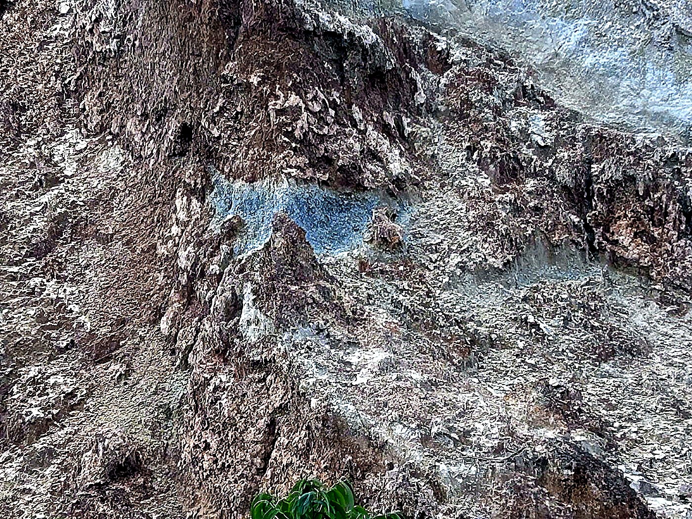 A steep rock wall showing a pale mineralised vein running horizontally through darker host rock