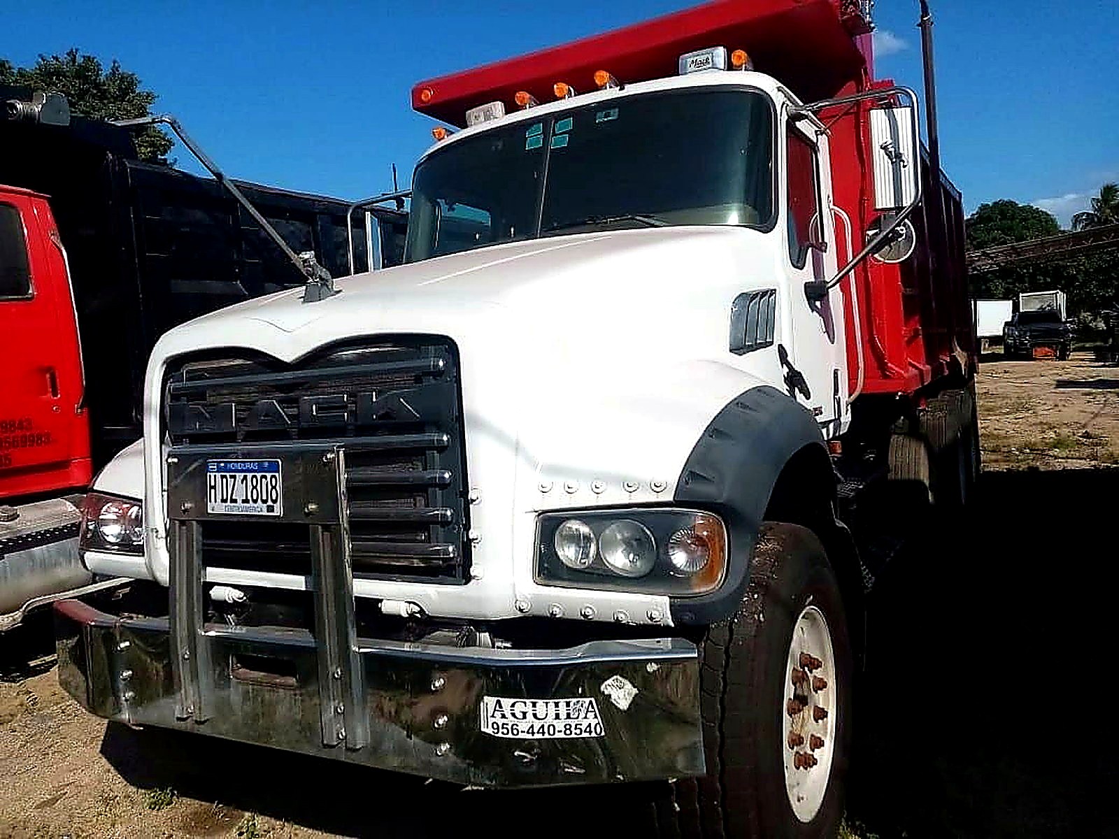 A white and red tipper haul truck parked on a dirt yard at a Central American mine site