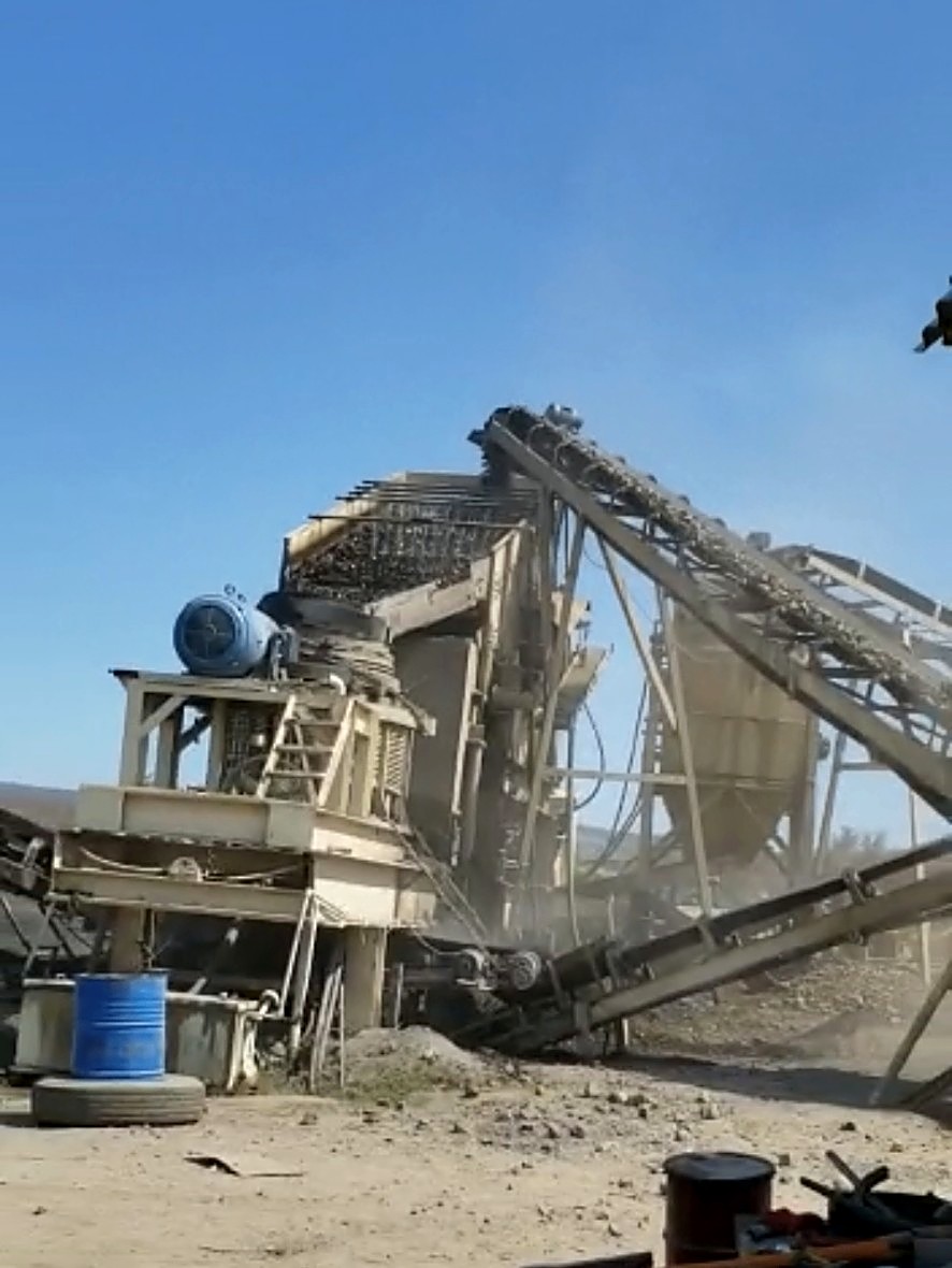 Dust rising from an operating crushing plant and conveyor line on a sunny day