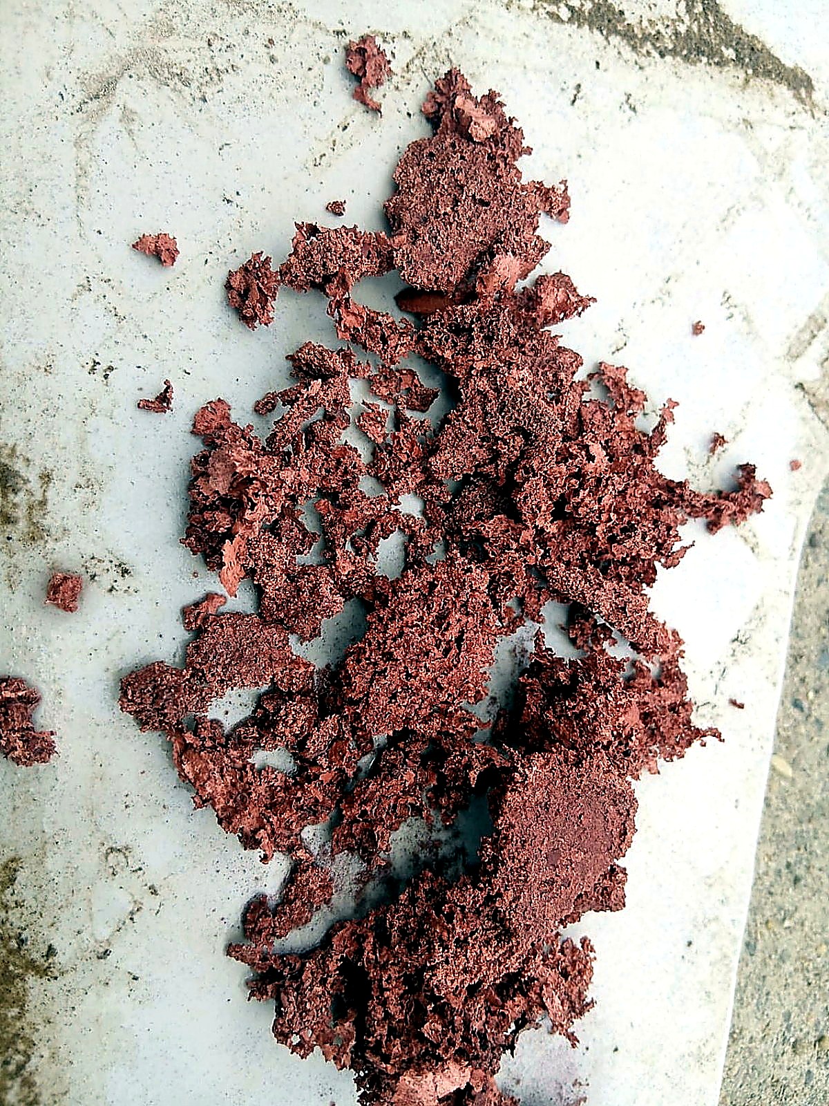 Reddish-brown sponge-like copper precipitate spread across a white ceramic tile